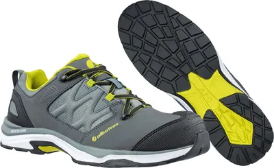 A pair of grey and yellow low-cut safety shoes are shown against a white background. One shoe is shown from the side, and the sole of the other shoe is shown from underneath.
