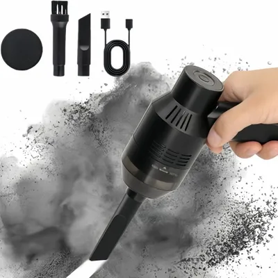 A hand holding a mini vacuum cleaner that is cleaning up a cloud of dark dust.