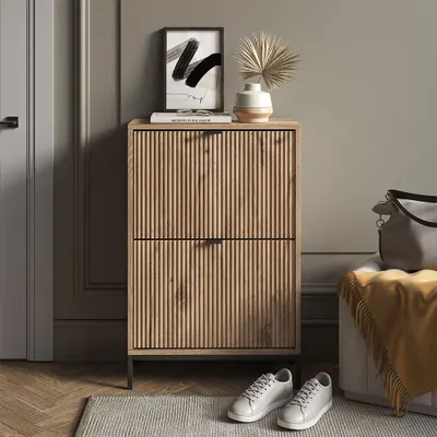 A hallway or entryway scene featuring a wooden shoe cabinet, shoes, and a bag.