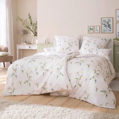 A neatly made bed with floral patterned bedding in a bright, airy bedroom.
