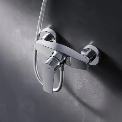 A close-up shot of a chrome shower faucet mounted on a textured gray wall.