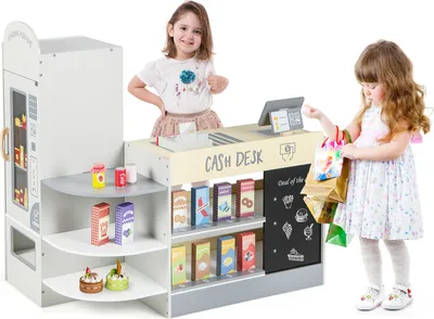 Two young girls playing with a wooden toy supermarket set.