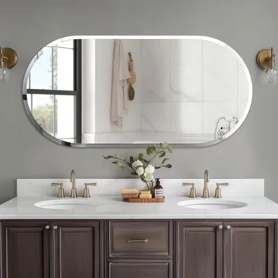 A modern bathroom vanity with a large oval mirror above it, featuring two sinks and faucets.