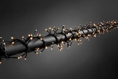 A string of LED cluster lights wrapped around a black cylindrical object against a dark gray background.