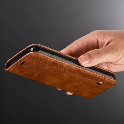 A hand holding a brown leather phone case.