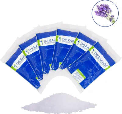 A product shot of six bags of Therabath paraffin wax, with a sprig of lavender in the upper right corner and a pile of paraffin wax beads in the foreground.