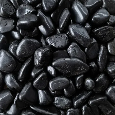 Schwarze polierte Kieselsteine dicht aneinander liegend im Detail, KI-generiertes Bild