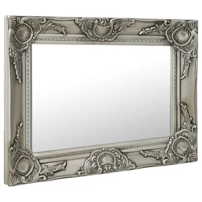 A silver baroque-style wall mirror is shown from a diagonal angle against a white background.
