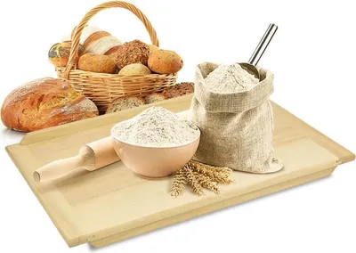 A collection of baked goods and flour is displayed on a wooden board.