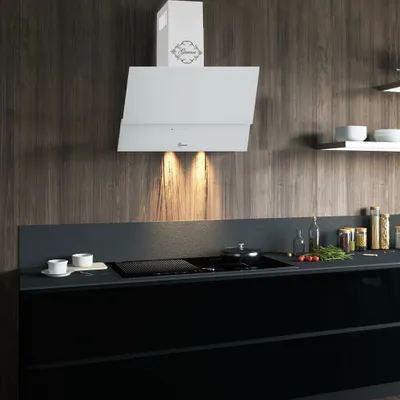 A modern kitchen with a white range hood over a black stovetop and cabinets.