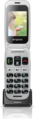 A flip phone in a charging cradle, with a picture of a child on the screen.
