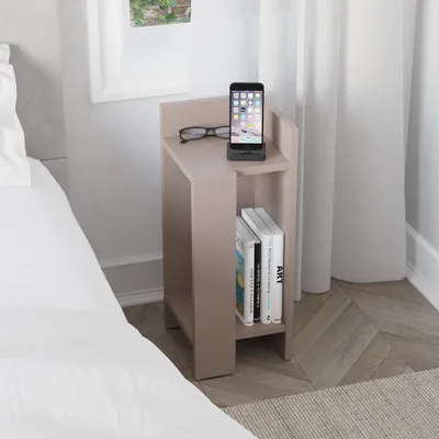 A modern nightstand with books and a phone docked on top, placed next to a bed.