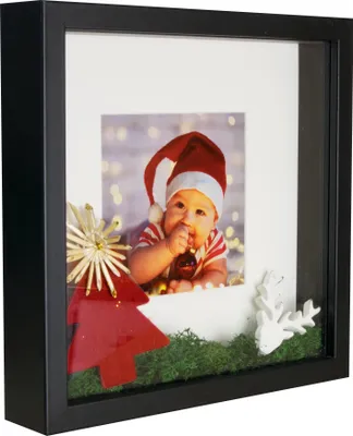 A shadow box frame with a baby in a Santa hat, Christmas decorations, and a photo of the baby.