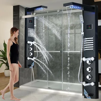 A woman stands next to a modern shower panel system with multiple water jets and a waterfall feature.