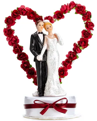 Tortenaufsatz Hochzeitspaar mit rotem Rosenherz, Braut in weißem Kleid und Bräutigam im schwarzen Anzug auf Sockel mit roter Schleife.