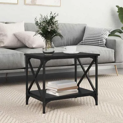 A black side table with a shelf is placed in a living room setting next to a gray sofa.