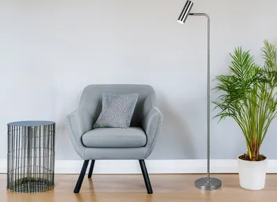 A minimalist living room scene with a gray armchair, a side table, a floor lamp, and a potted plant.