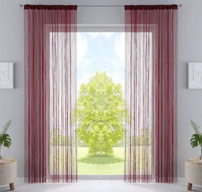 A window with burgundy string curtains and a view of a green tree outside.