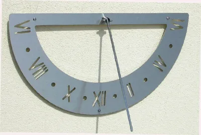 A metal sundial with Roman numerals mounted on a textured wall.