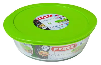 A Pyrex glass bowl with a green lid, shown from a slightly elevated angle against a white background.