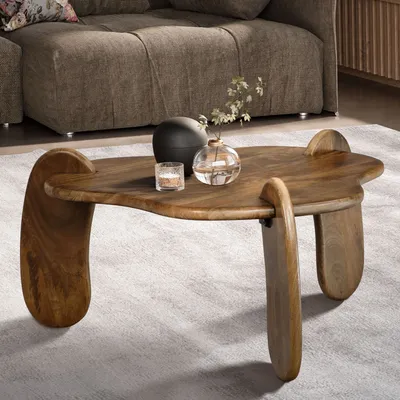 A wooden coffee table with decorative items on it, placed in a living room setting with a sofa in the background.