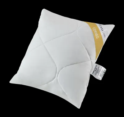 A white pillow with a yellow and white tag on it, set against a black background.