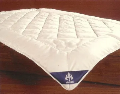 A white quilted blanket or duvet is laid out on a wooden surface.