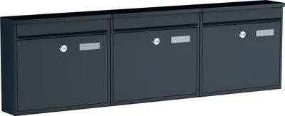 A set of three dark gray mailboxes mounted on a wall.