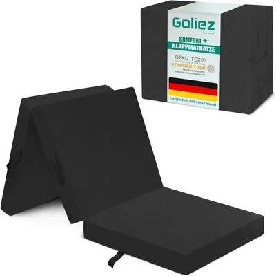 A folded black mattress is shown in front of its packaging.