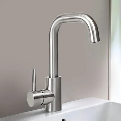 A modern stainless steel kitchen faucet is shown in a studio setting, placed on a white sink.