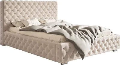 A beige upholstered bed with a tufted headboard and footboard, shown from a side angle with bedding.