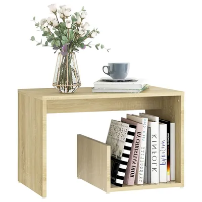 A light brown wooden side table with books and a vase of flowers on top.