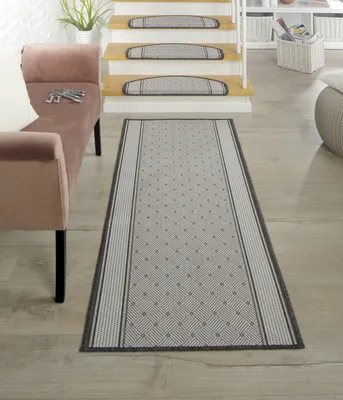 A hallway with a runner rug and stair treads.