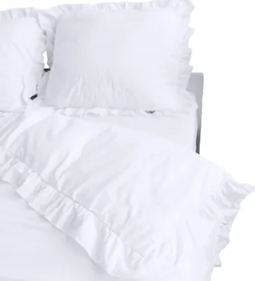 A close-up view of white bedding with ruffled edges, including a pillow and a duvet cover.