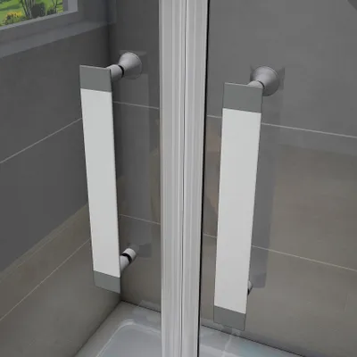 Close-up view of two modern shower door handles against a tiled wall.