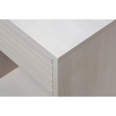 A close-up view of the corner of a white wooden nightstand, showing its slatted drawer front and smooth top surface.