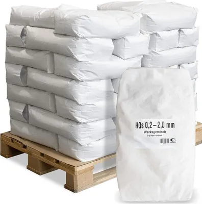 A stack of white bags on a wooden pallet, with one bag in the foreground showing a label.