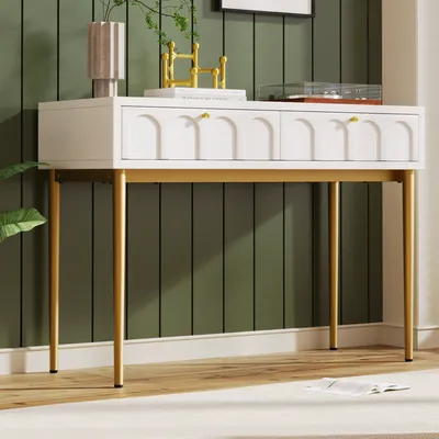 A white sideboard with gold legs is placed against a green paneled wall, decorated with a vase and a gold sculpture.