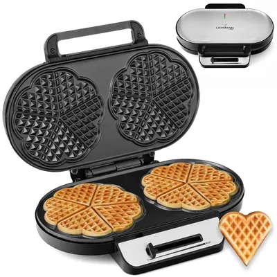 A waffle maker is shown open, with two heart-shaped waffles cooked on the bottom plate and the empty molds on the top plate. A single heart-shaped waffle is also shown next to the waffle maker.
