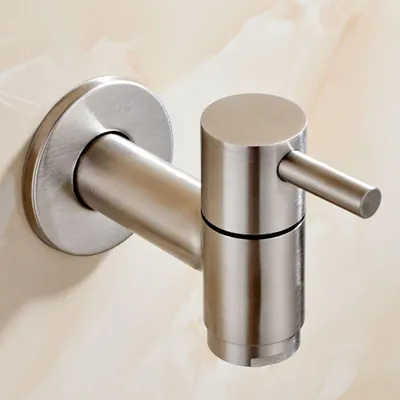 A close-up shot of a brushed stainless steel wall-mounted faucet against a marble-patterned wall.