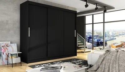 A black sliding door wardrobe in a modern living room with a large window overlooking a city.