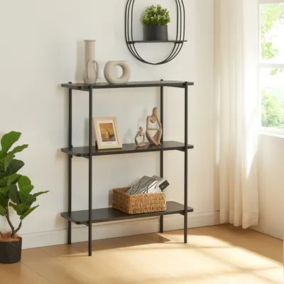 A black three-shelf shelving unit is displayed against a white wall, with decorative items on the shelves and a plant to the left.