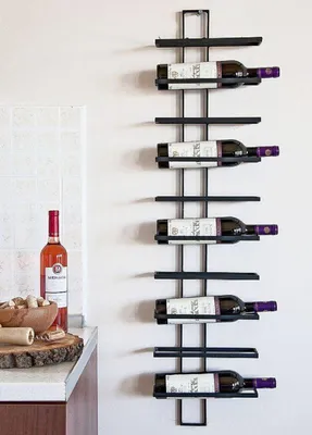 A wine rack mounted on a wall next to a kitchen counter with a bottle of wine and corks.