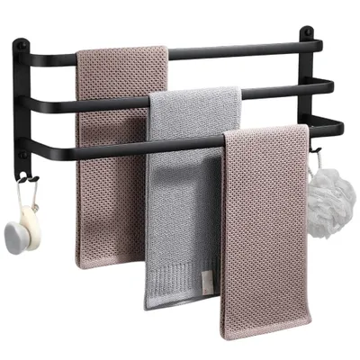 A black aluminum towel rack with three bars, holding three different towels and a bath puff.