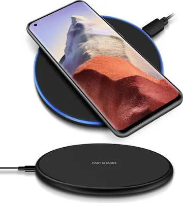 A smartphone is wirelessly charging on a black charging pad, with a second charging pad visible below.