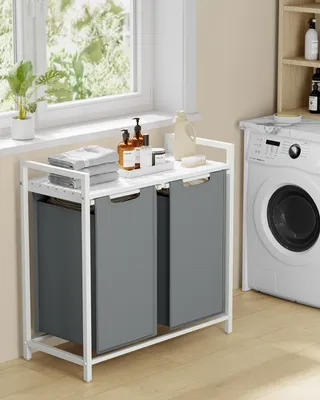 A laundry basket with two compartments and a shelf, placed next to a washing machine.