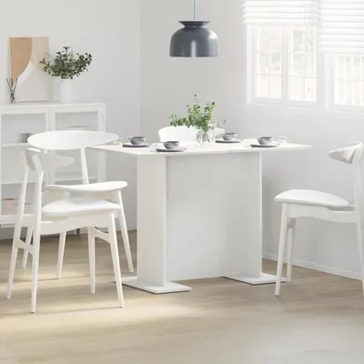 A white dining table set with white chairs in a bright, modern room.