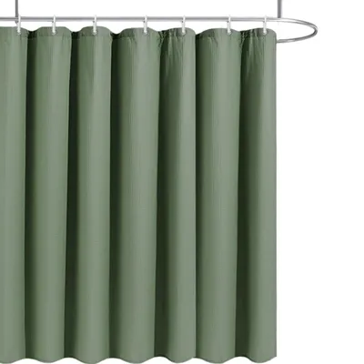 A sage green shower curtain hanging from a shower rod.