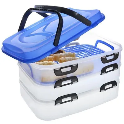 A stack of three clear plastic food containers with blue lids and black handles, one of which is open to reveal cookies on a blue rack inside.