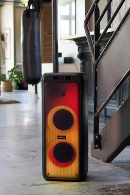 A large portable speaker with disco lighting is placed on the floor next to a staircase in a room.
